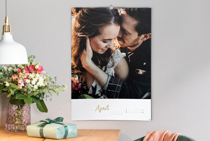 Een kalenderblad voor april met een romantische foto van twee omarmende personen, bloemen en een cadeau.