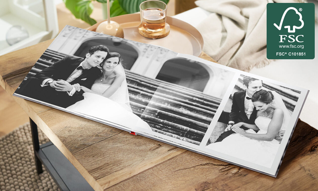 Een geopend fotoboek met trouwfoto's op een tafel. De foto's tonen een bruidspaar in elegante kleding.