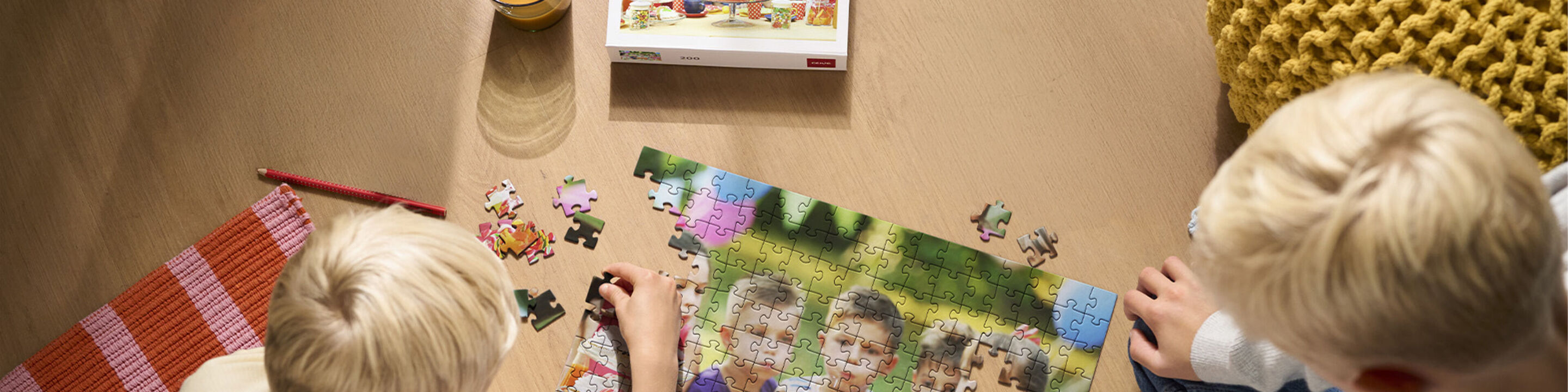 Twee blonde jongetjes puzzelen de laatste stukjes van een puzzel van een verjaardagsfeestje.