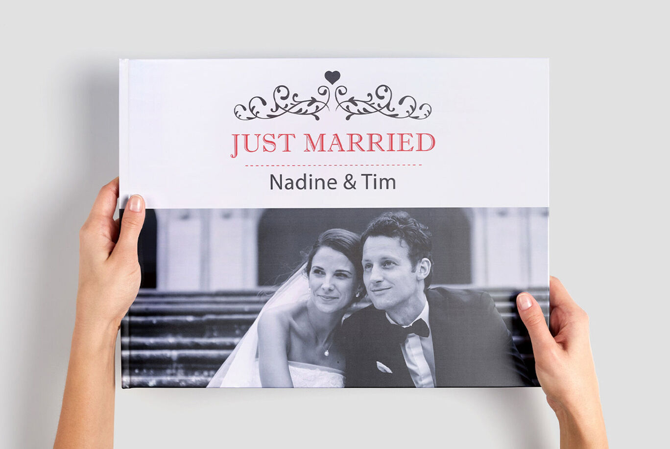 Een paar houdt hun persoonlijke fotoboek 'Just Married' vast. Het trouwboek toont de namen Nadine en Tim.
