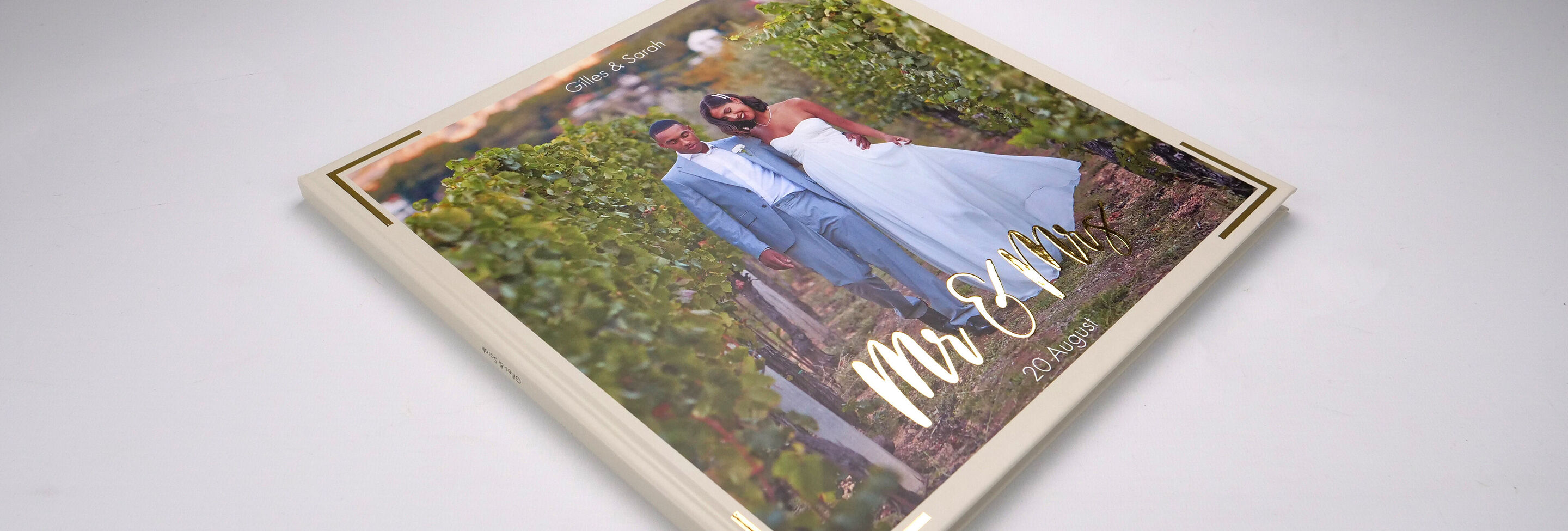Een elegant CEWE fotoboek met de titel 'Mr & Mrs' op een tafel, omringd door wijnstokken.