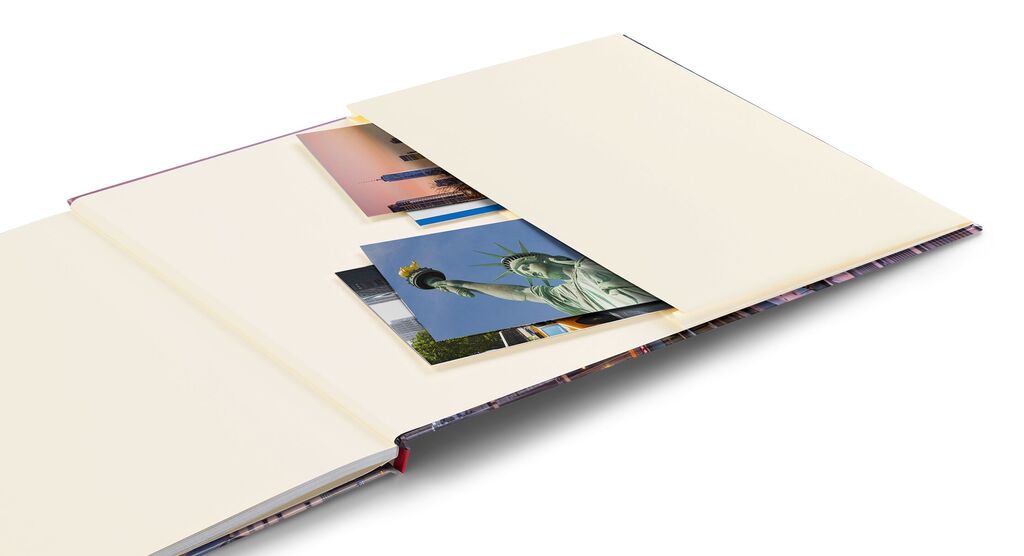 Een geopend CEWE fotoboek met beige pagina's, met foto's zoals het Vrijheidsbeeld en een stadsgezicht.