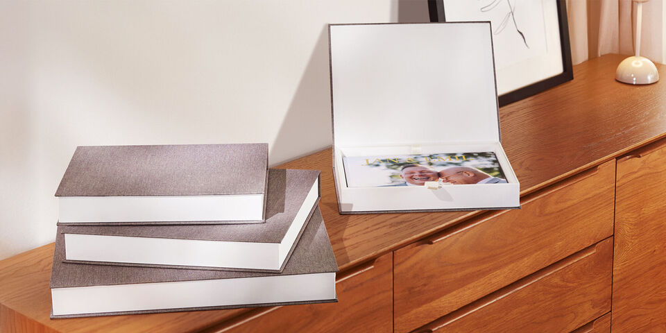 Verschillende CEWE fotoboeken netjes gestapeld op een houten dressoir, eentje open met foto's.