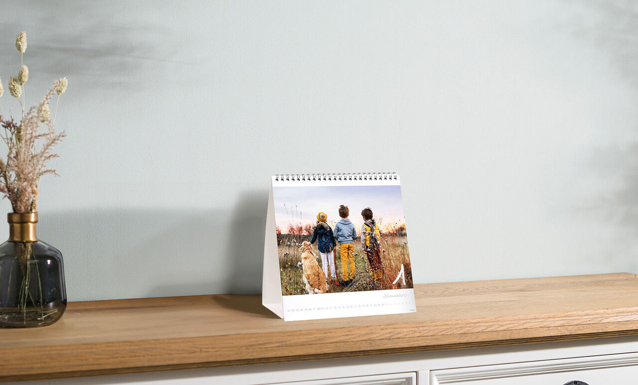 Drie personen staan in een veld en kijken naar de zonsondergang, omgeven door natuur.