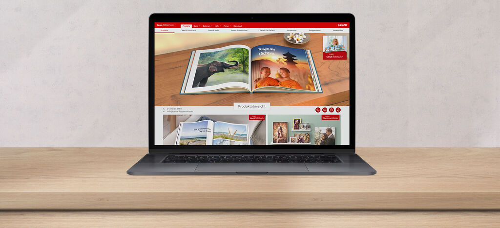 Een laptop met de CEWE FOTOVOEK-website geopend op een houten tafel.