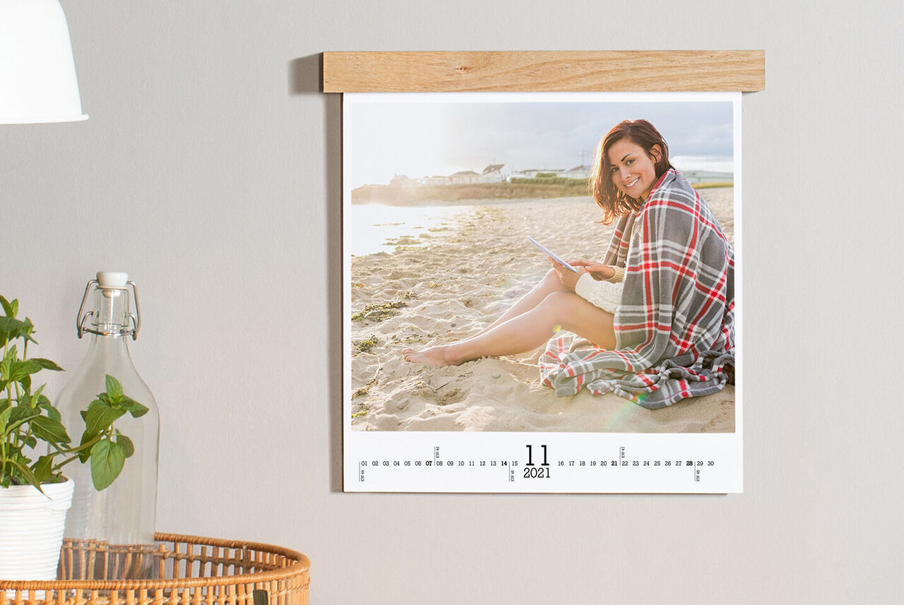 Wandkalender met een maand en een persoon die op het strand zit.