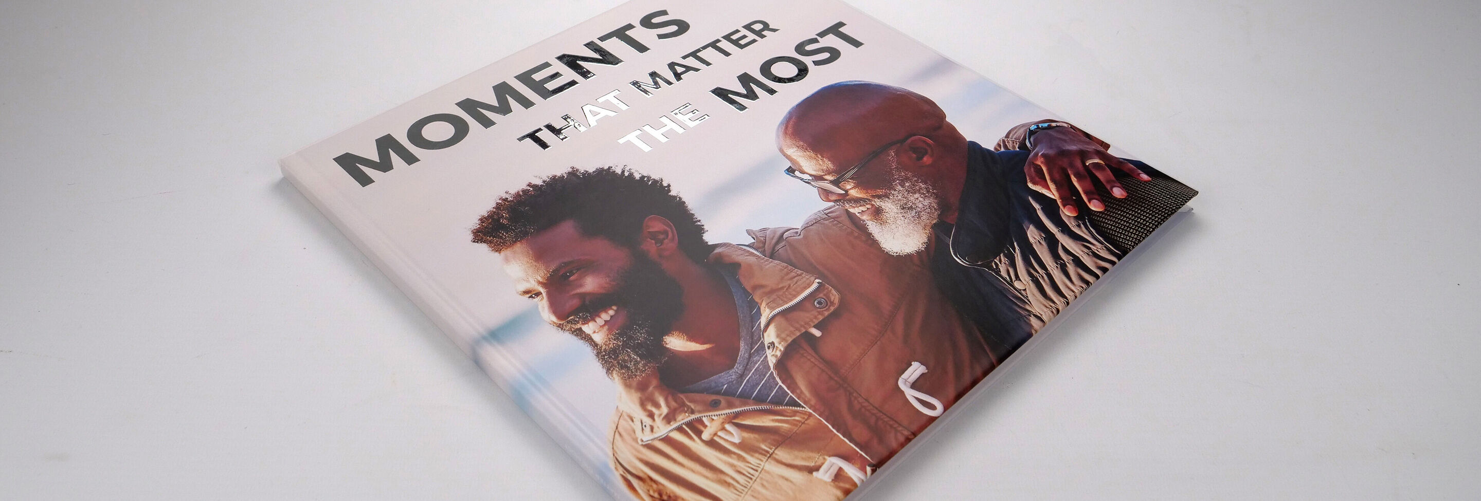 Een CEWE fotoboek met de tekst 'Moments That Matter Most', dat twee mensen toont die samen een gelukkig moment delen.