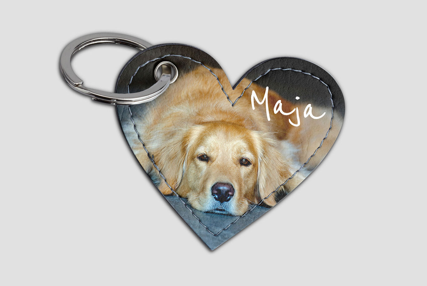 Een hartvormige sleutelhanger met de foto van een Golden Retriever genaamd Maja, die ontspannen ligt