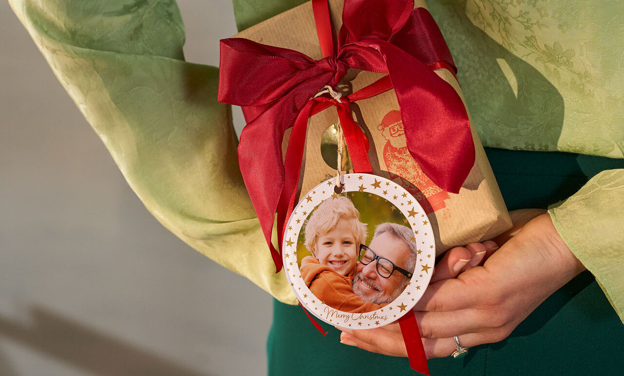 Iemand houdt een mooi ingepakt cadeau met een rood lint vast.