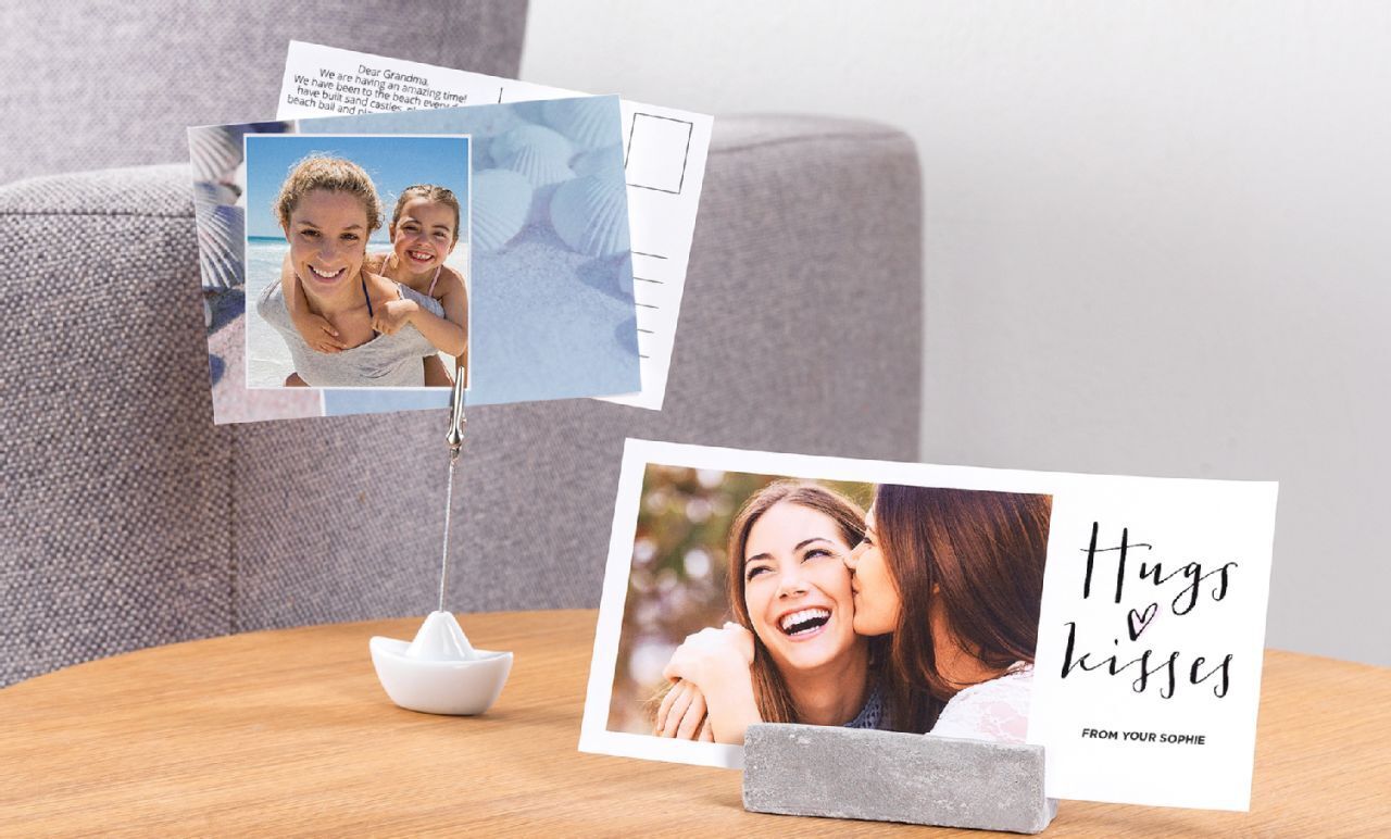 Twee liefdevol ontworpen wenskaarten op een tafel, één toont een paar, de andere bevat de tekst 'Hugs & kisses'.