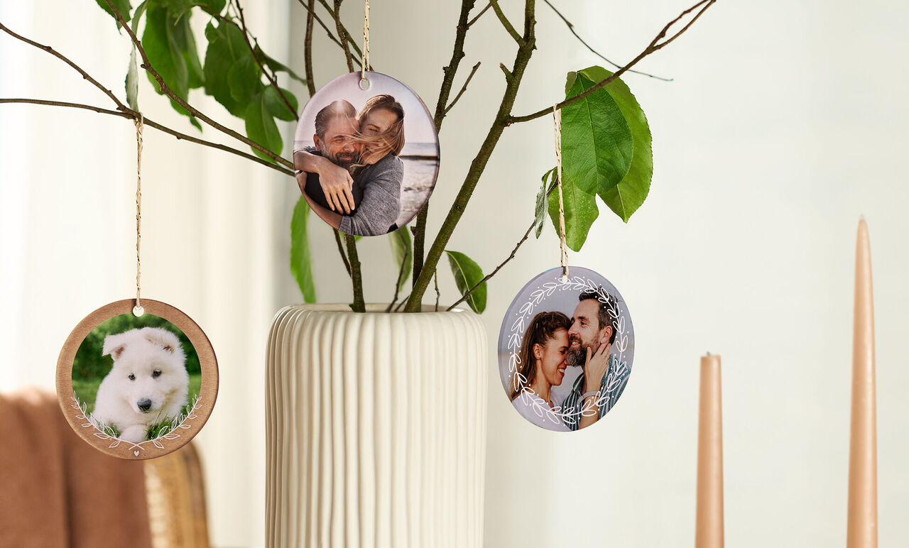 Drie ronde afbeeldingen hangen aan een decoratieve tak in een vaas.