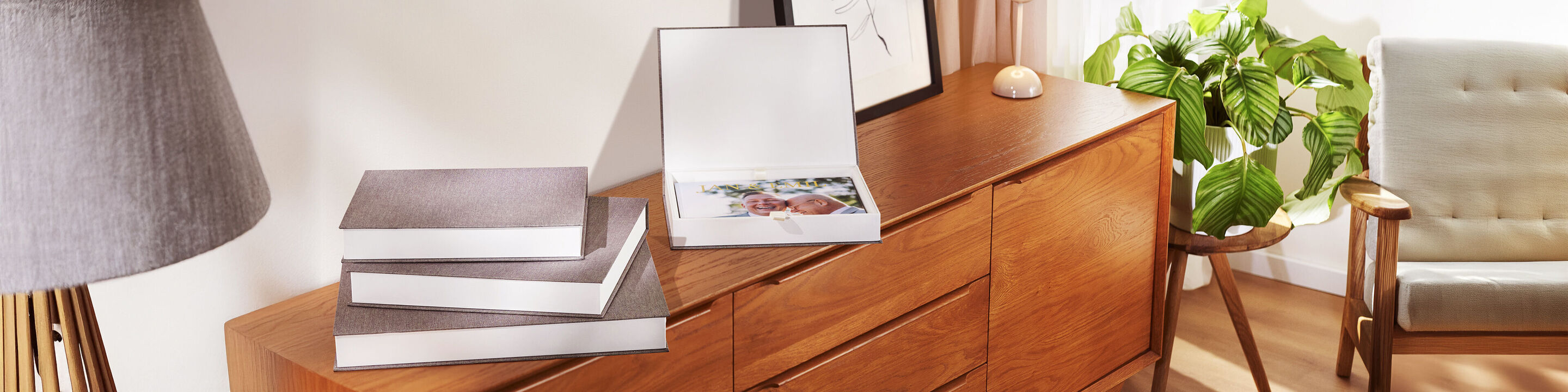 Drie mooie fotoboeken in een lichte woonkamer op een houten kast.