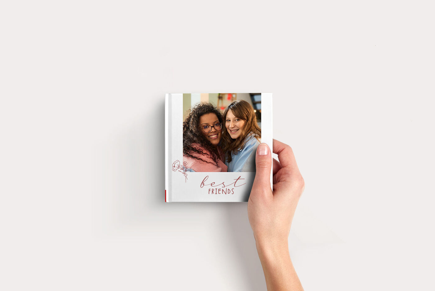 Klein fotoboekje Compact Vierkant met een foto van twee vriendinnen en de tekst “best friends”, vastgehouden door één hand.