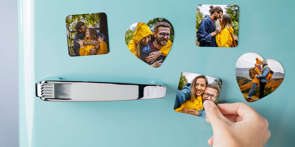 Een hand pakt een hartfoto van een koelkast, omringd door hartfoto's en een zilveren handvat.