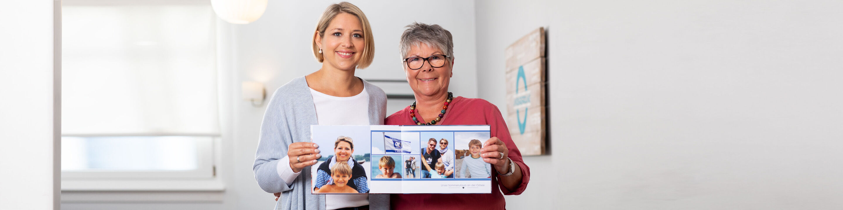Twee personen houden blij een fotoboek vast. Het toont gelukkige momenten en herinneringen.
