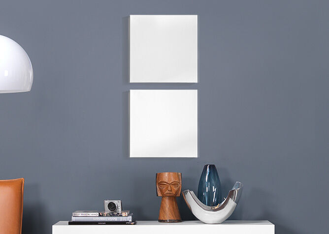 Twee lege witte kaders aan een grijze wand boven een tafel met decoratie-objecten.