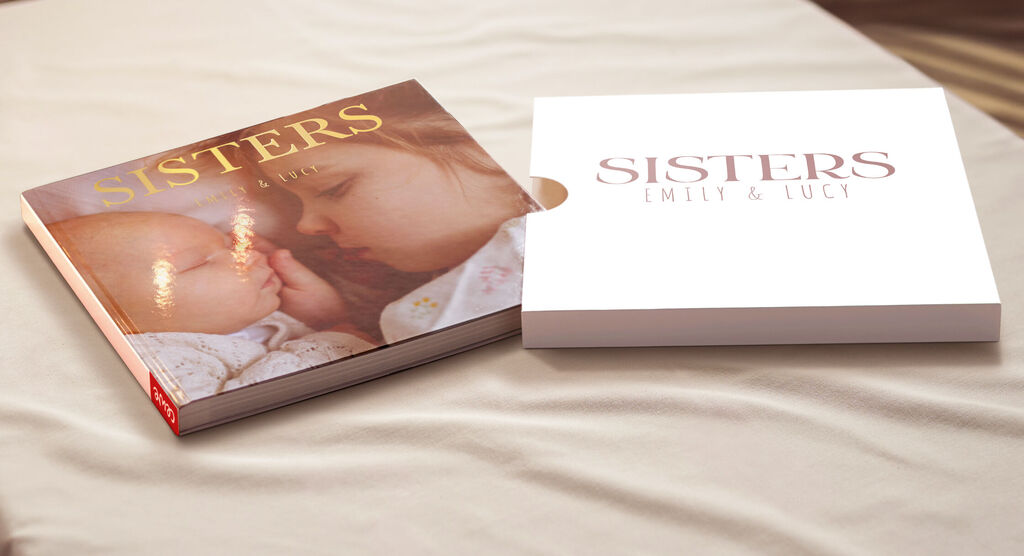 Een open CEWE fotoboek "Sisters" op tafel, met twee zussen op de cover.