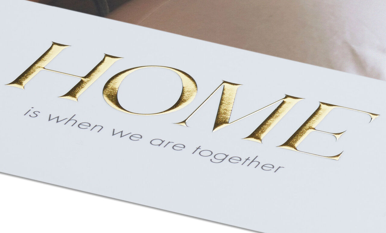 Muurdecoratie met "HOME is when we are together" in goud en grijs.