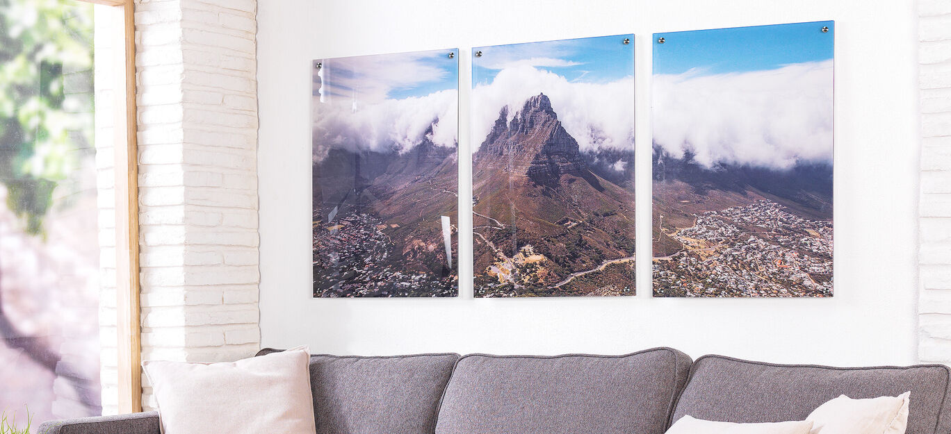 Drie wandfoto’s van bergen met wolken op de achtergrond.