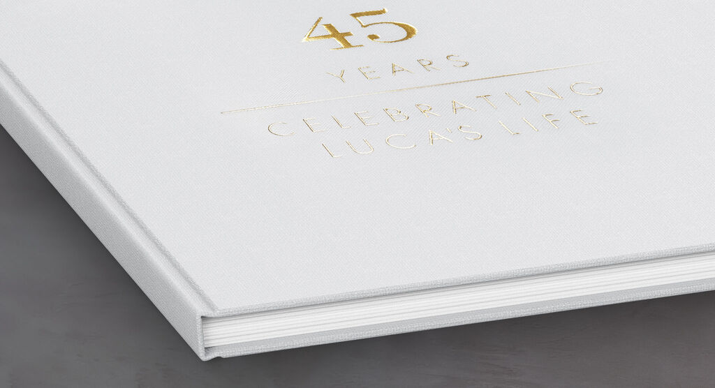 Een wit fotoboek met gouden opdruk voor een 45e verjaardag gemarkeerd door CEWE FOTOOBOEK.