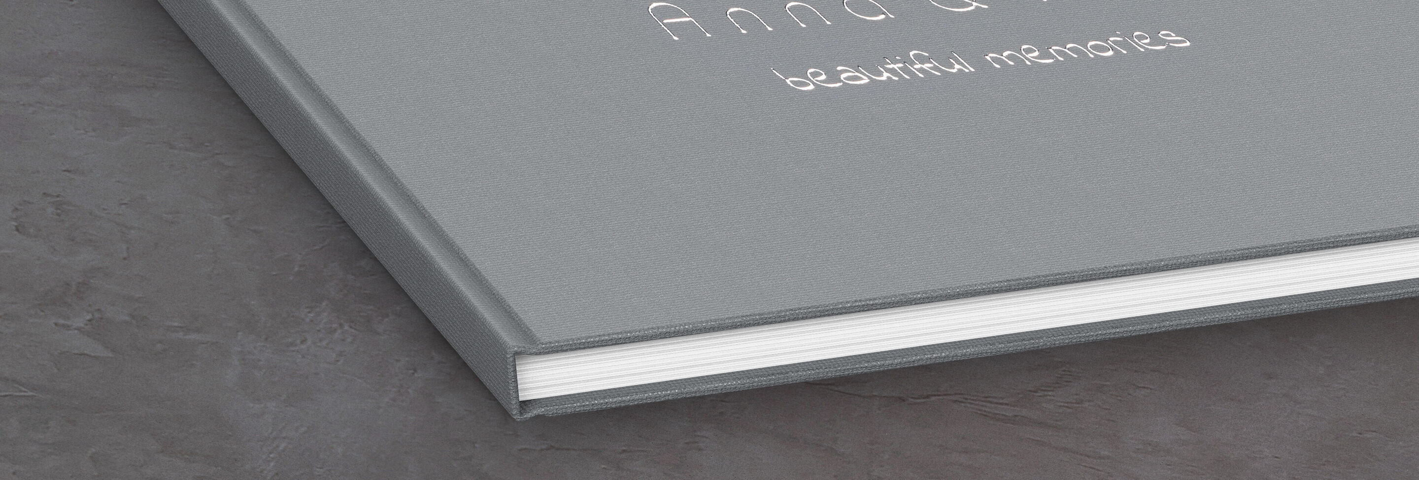 Grijs CEWE Fotoboek met de titel 'Anna &' en de ondertitel 'beautiful memories' op een tafel.