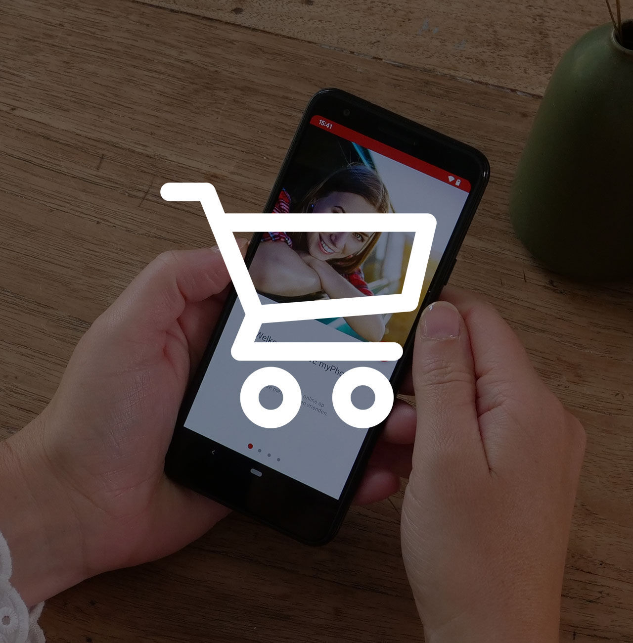 Handen houden een smartphone vast met een winkelwagenpictogram.