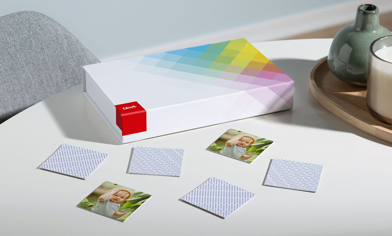 CEWE Fotoboek op tafel, omringd door kleine foto's en een vaas