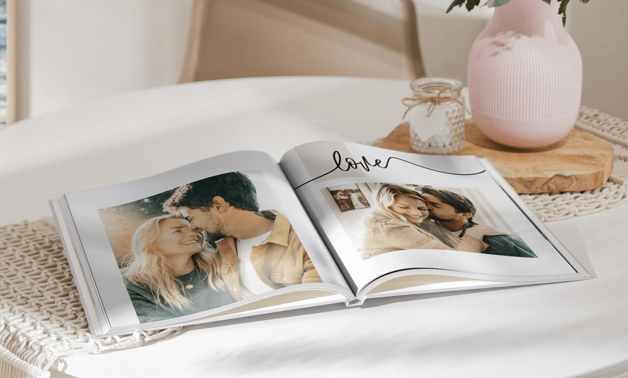 Open fotoboek op een tafel met twee foto's van een paar en het woord 'liefde'.