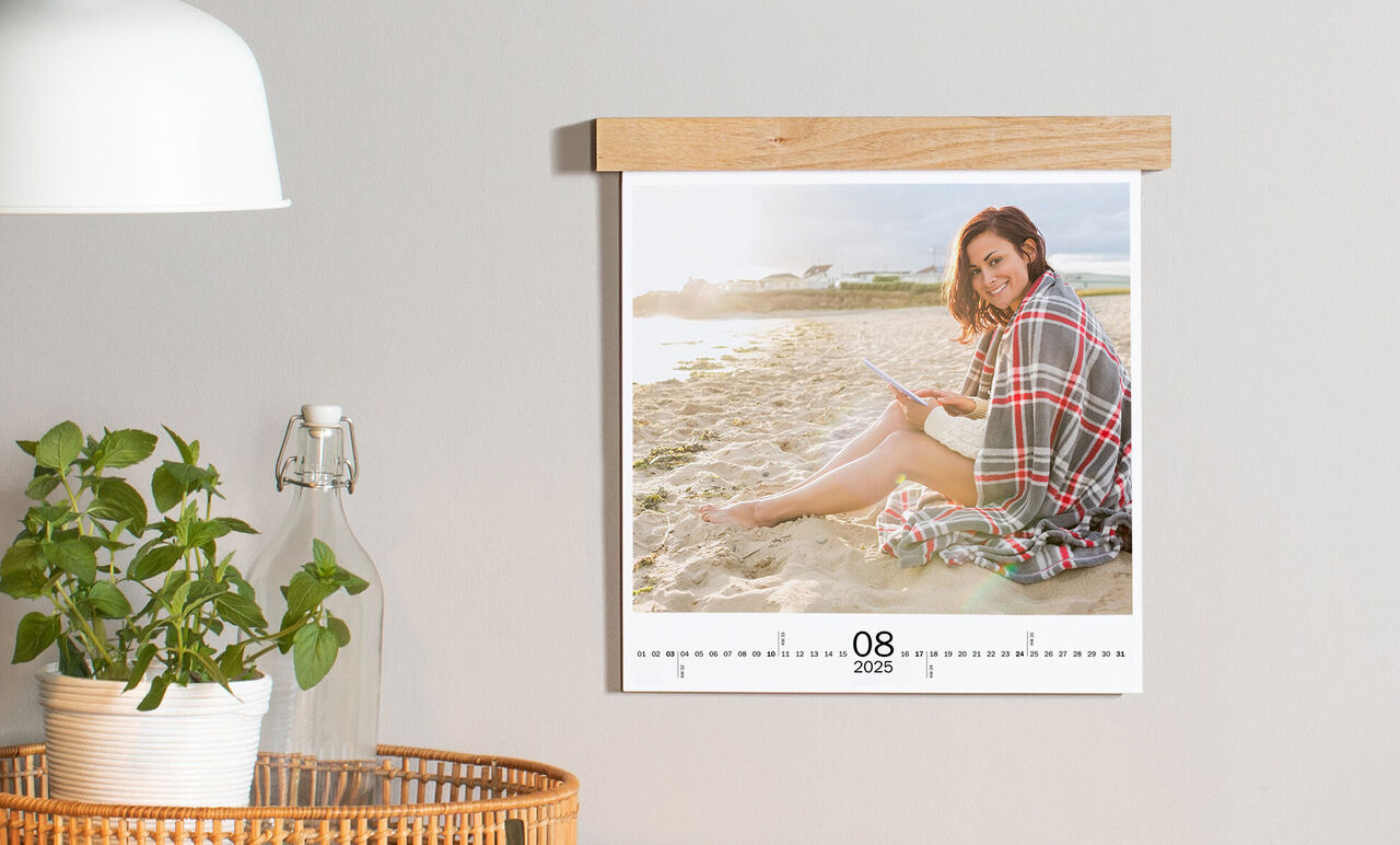 Persoon leest een boek op het strand in een CEWE Fotokalender van augustus 2025
