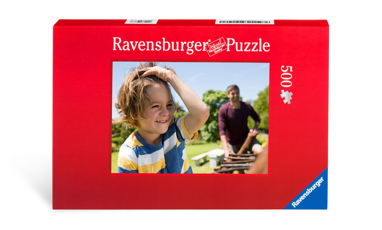 Een jongen met krullend haar en een gestreept shirt werkt aan een Ravensburger puzzel buiten.