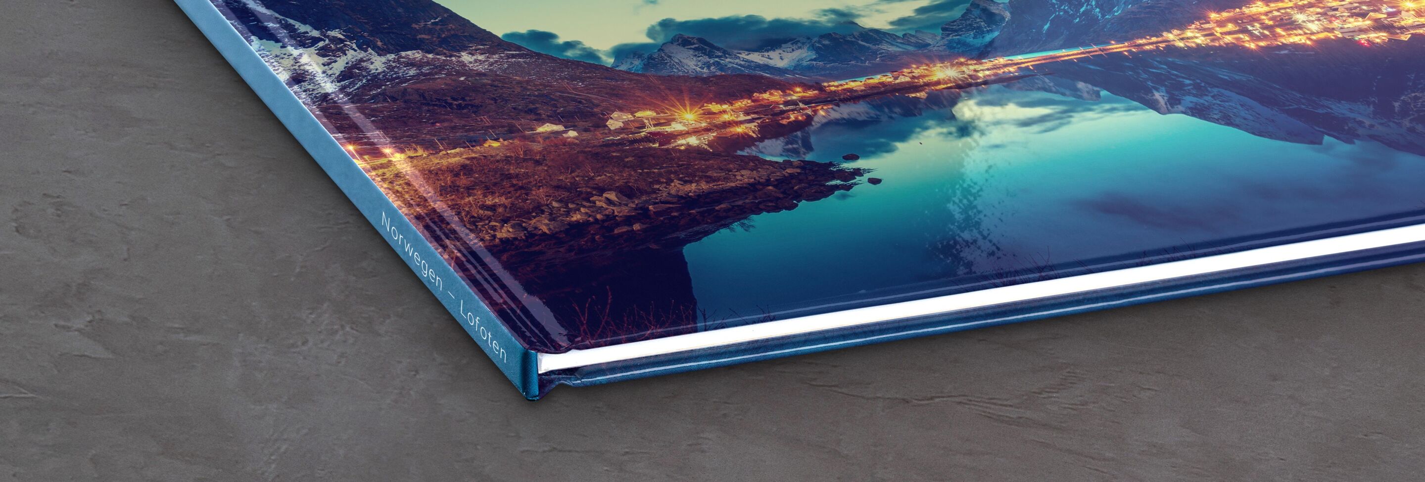 CEWE FOTBOEK met een prachtig landschap op de omslag, dat oranje lichten toont die in het water weerspiegelen.