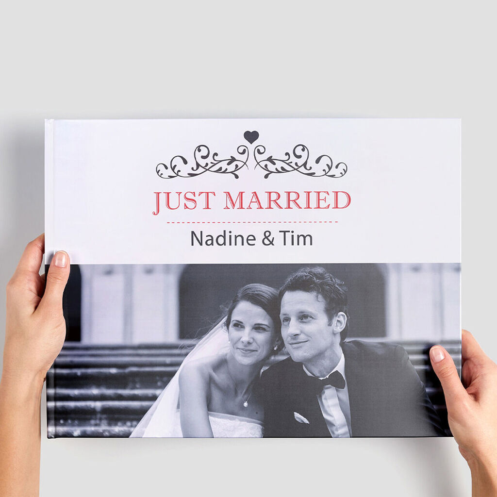 Bruid en bruidegom houden een CEWE fotoboek met de titel 'Just Married' vast.