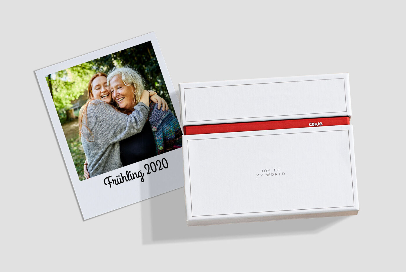 Een liefdevolle foto van twee mensen die elkaar omarmen, naast een gepersonaliseerde CEWE geschenkdoos met rode strik.
