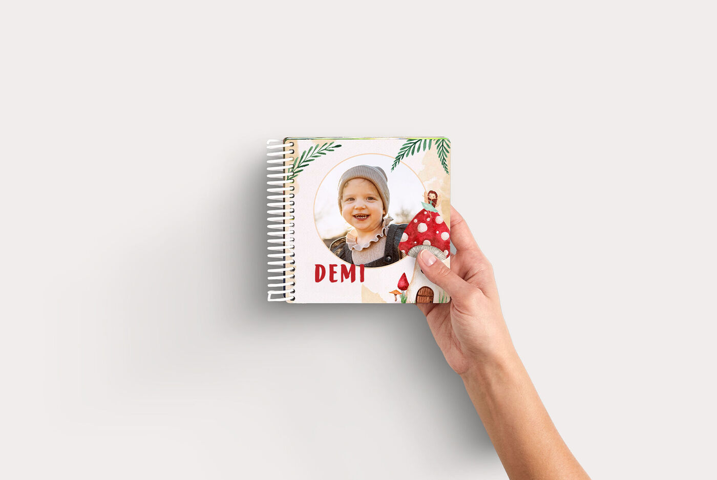 Spiraalgebonden fotoboek Kids met een kind op de cover en de naam “Demi”, vastgehouden door één hand.