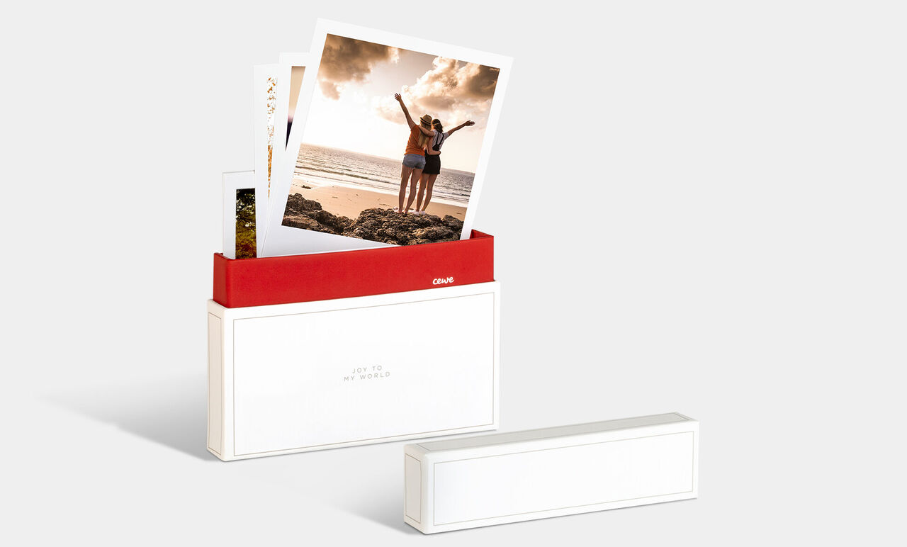 Een CEWE fotobox met foto's van twee vrolijke personen op het strand.