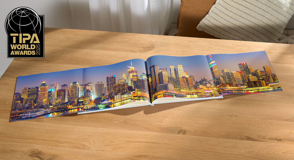 CEWE fotoboek met indrukwekkend skylinebeeld van een stad bij nacht op een tafel