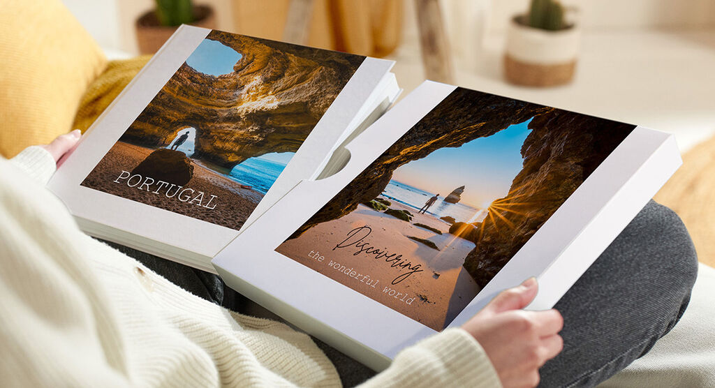 Twee CEWE fotoboeken met vakantiefoto's worden vastgehouden.