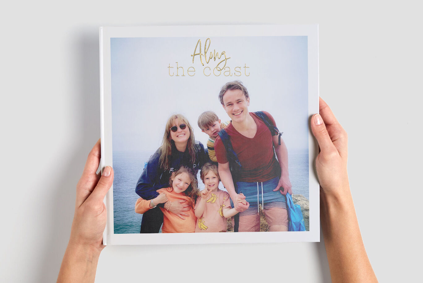 Een groep mensen houdt een CEWE Fotoboek omhoog dat hun gezamenlijke vakantie toont.