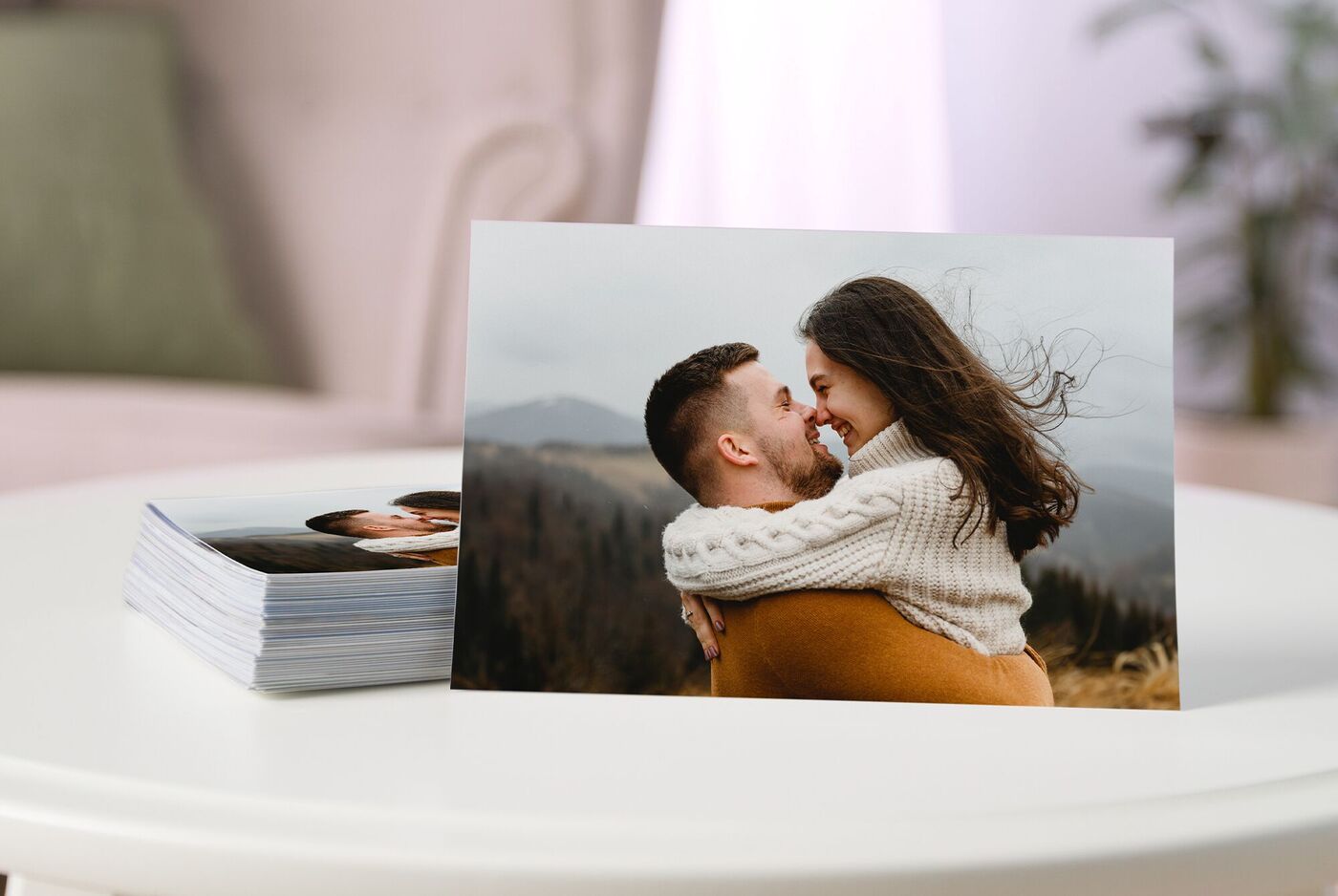 Een fotoafdruk van twee omhelzende mensen staat op tafel naast een stapel prints