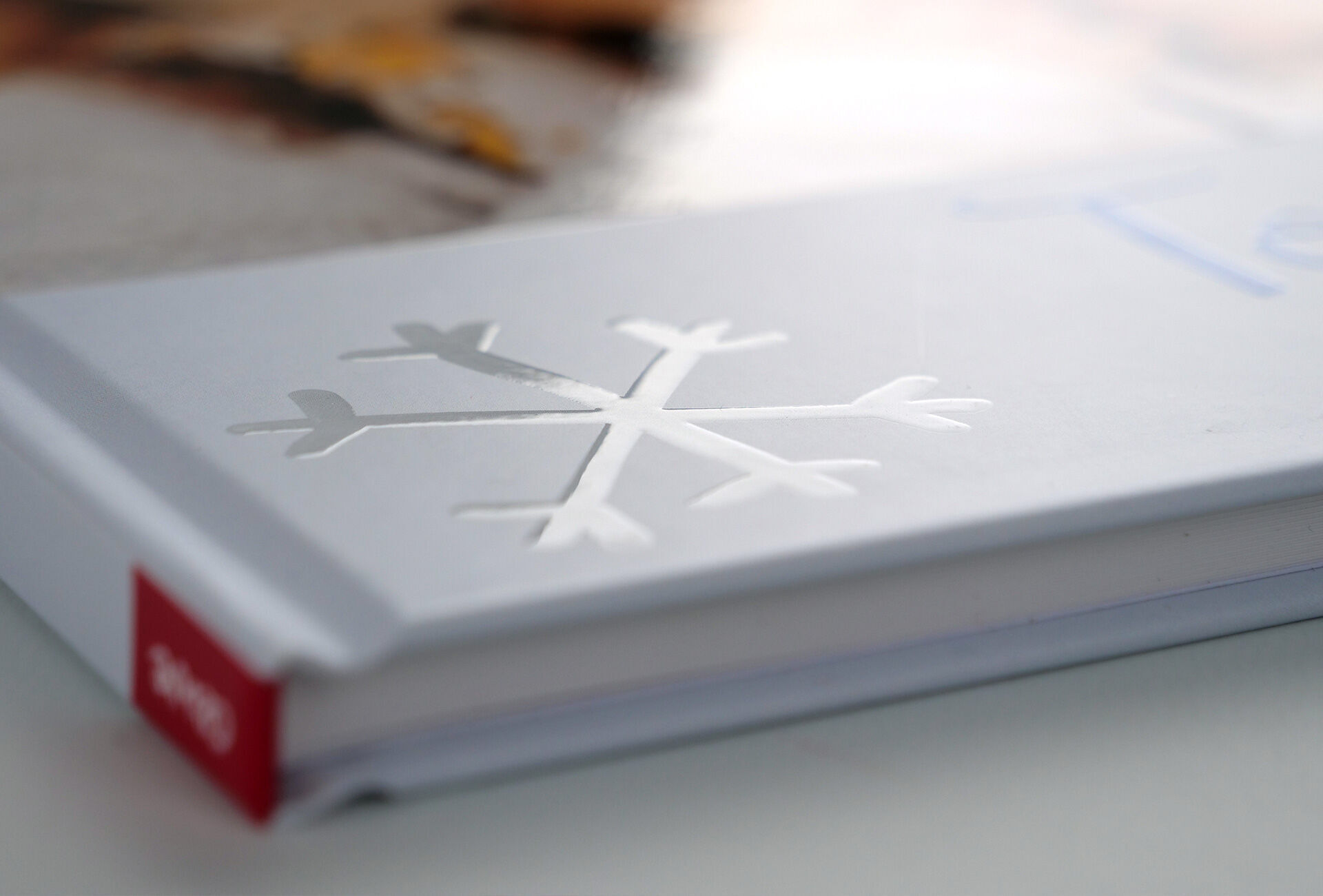 Een gedetailleerde close-up van de cover van een CEWE fotoboek met een sneeuwvlokontwerp en een elegante witte afwerking.