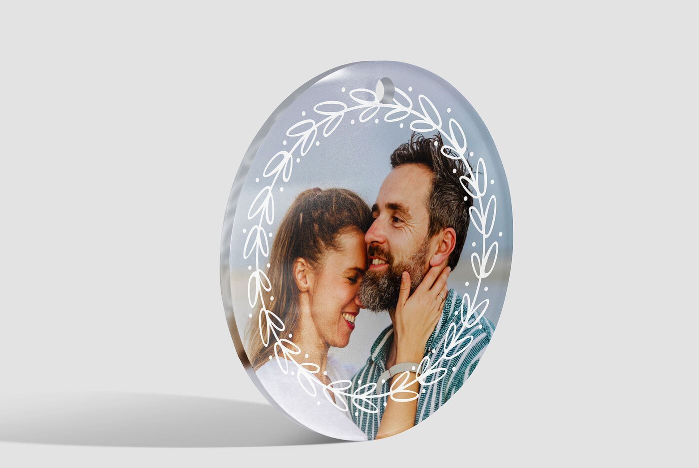 Een rond, transparant fotoproduct met een liefdevol stel en florale details op de achtergrond.