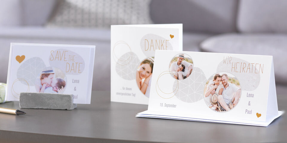 Drie feestelijke kaarten op een tafel: huwelijksuitnodiging, bedankkaart en save-the-date kaart
