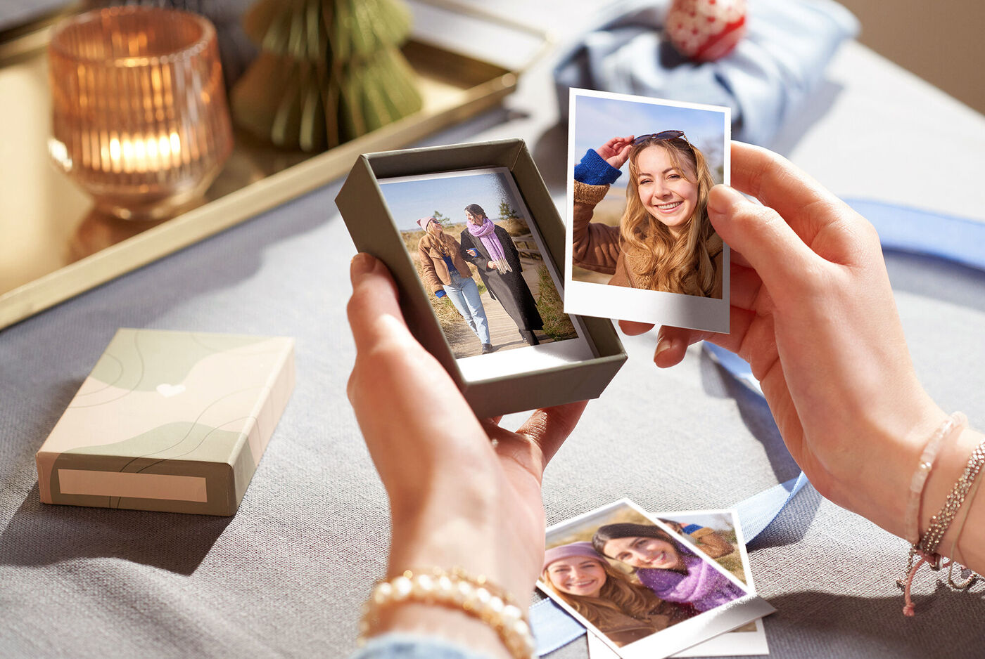 een persoon houdt een doos met fotoprints vast, omringd door foto's en stijlvolle decoratie