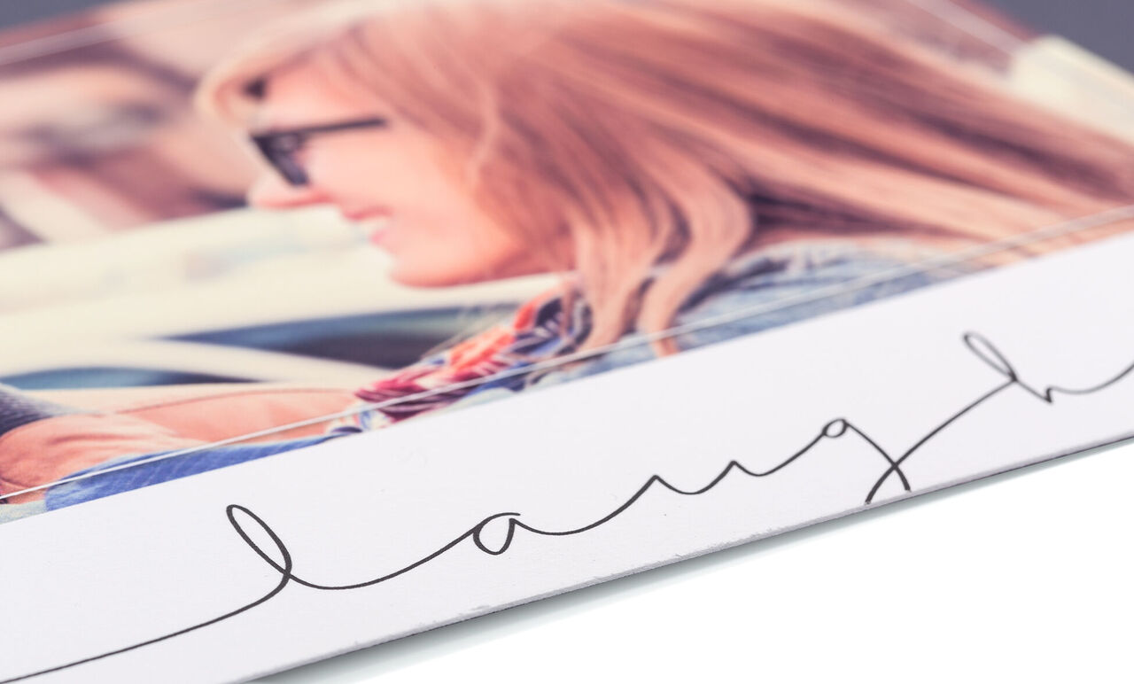 Detailweergave van een liefdevol ontworpen fotoboek met het woord "laugh" op de kaft