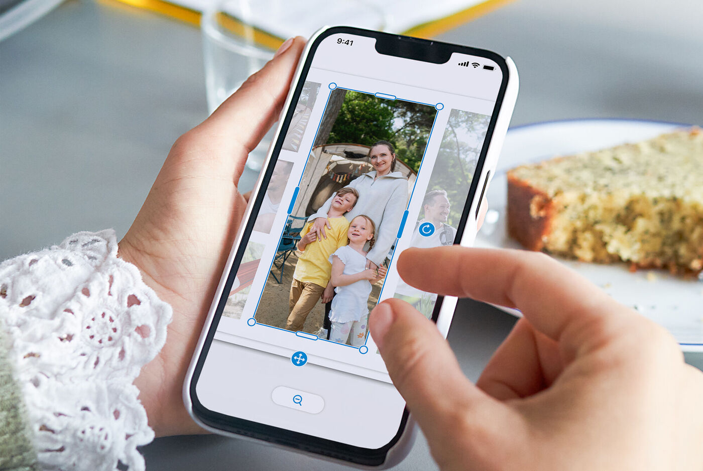 Een hand houdt een smartphone met een familiefoto vast. Iemand bewerkt het beeld. Een taartpunt is op de achtergrond zichtbaar.