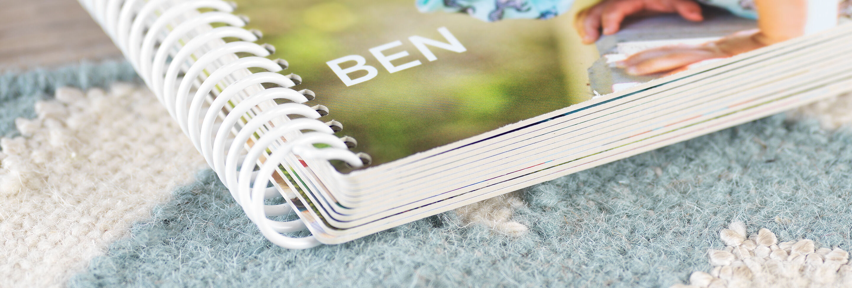 Close-up van een CEWE fotoboek met de naam "Ben" op een tapijt.