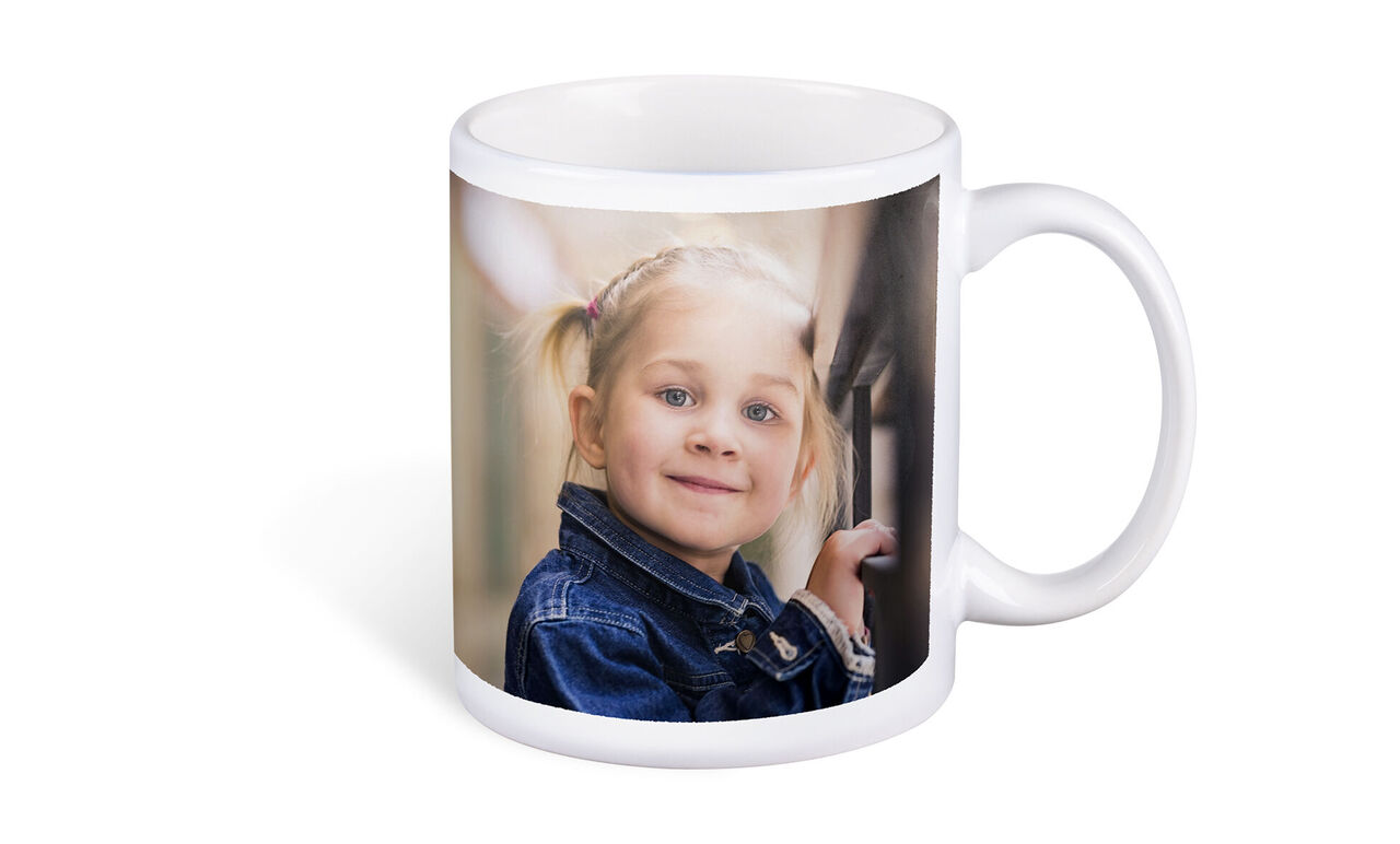 Een beker met een foto van een kind dat blij voor het raam staat