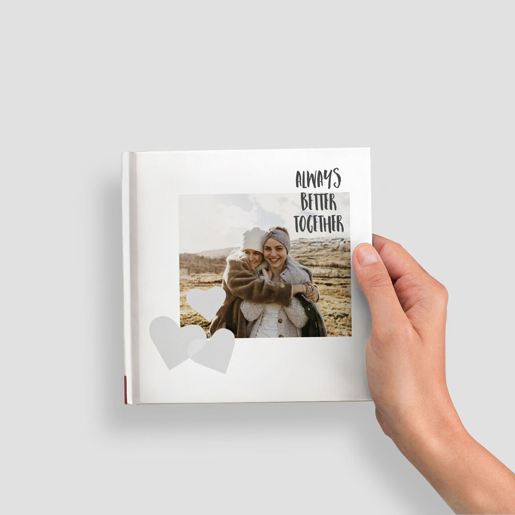 Iemand houdt een CEWE Fotoboek vast met een hartelijke foto van een paar op de omslag.