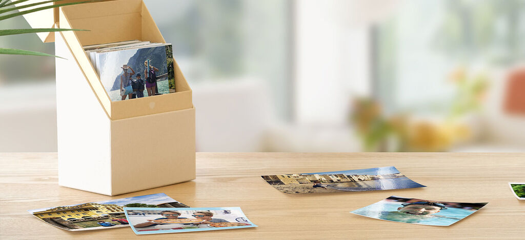 Een stijlvolle fotodoos met meerdere foto's eromheen op een tafel.