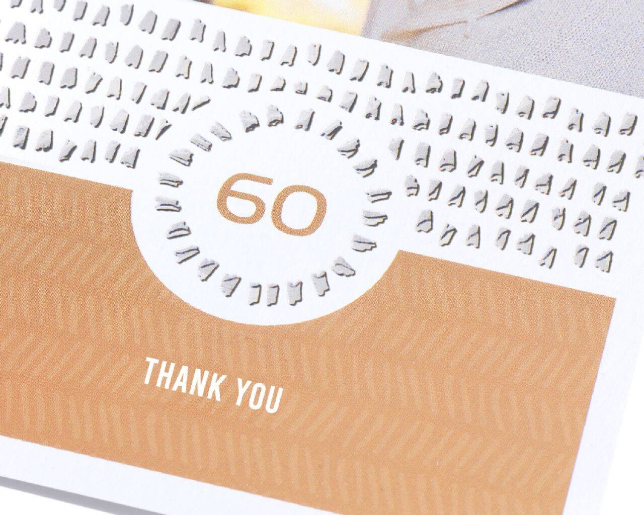 Een verjaardagskaart toont het cijfer 60 en de tekst "DANK JE" in elegant ontwerp.
